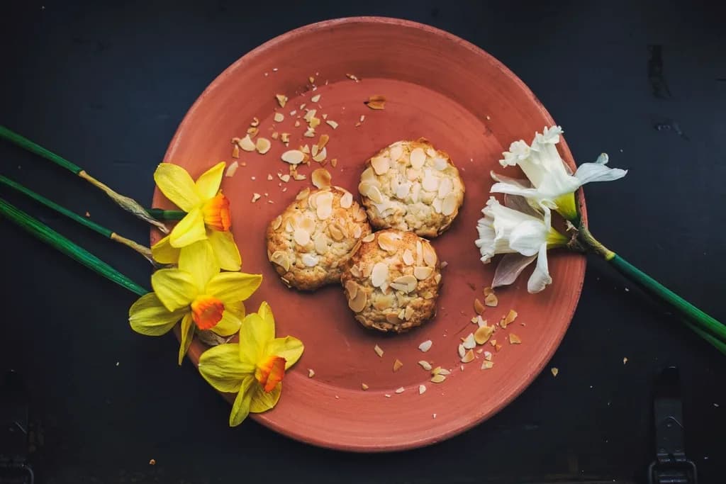 Tres galletas redondas cubiertas de almendra laminada en un plato de barro