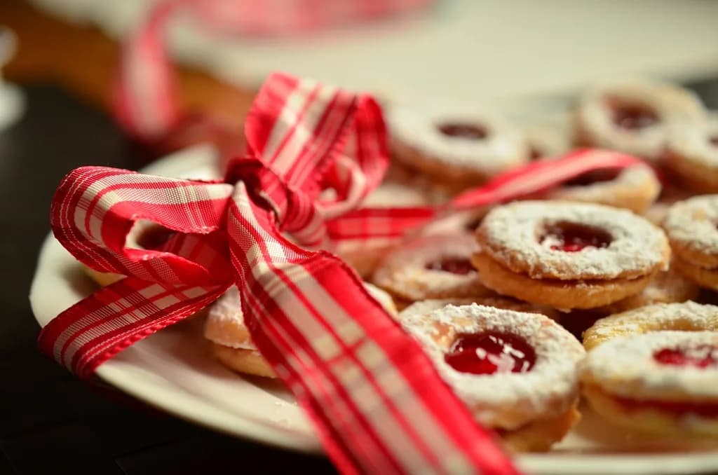 Galletas rellenas de mermelada de frambuesa con azúcar glas, en un plato